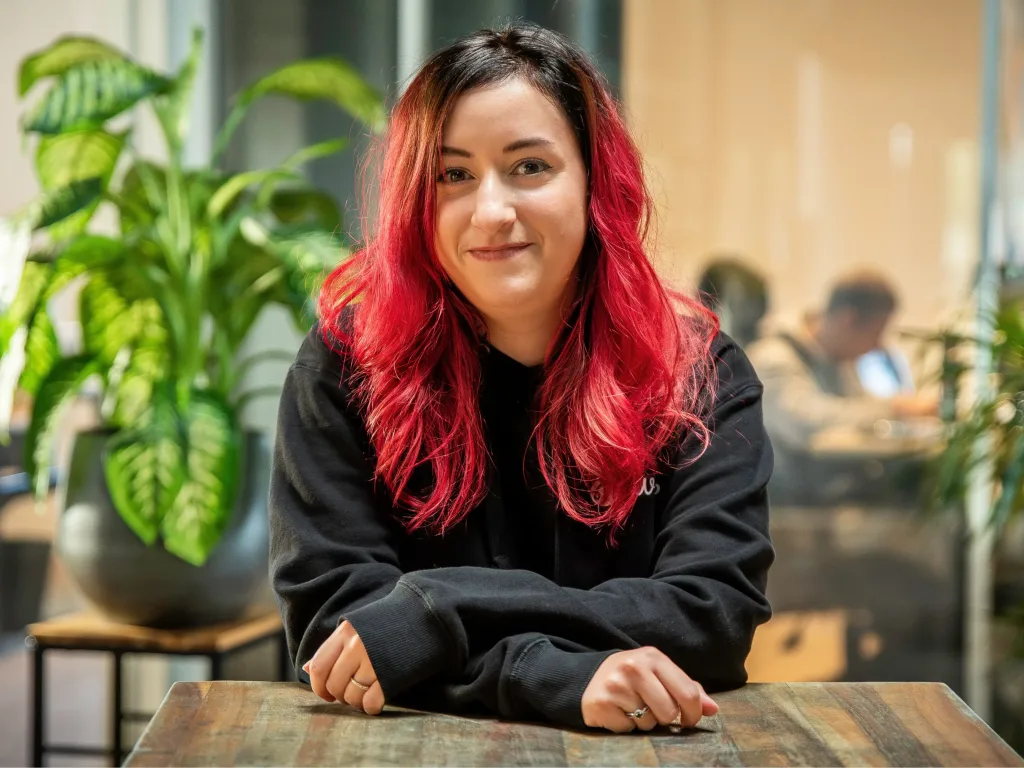 Jeune femme aux cheveux rouges souriante dans un espace de coworking