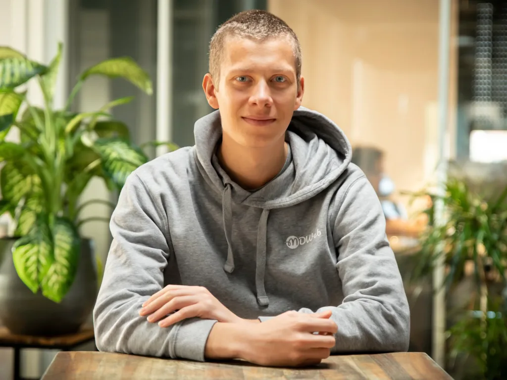 Jeune homme souriant en sweat gris dans un bureau moderne