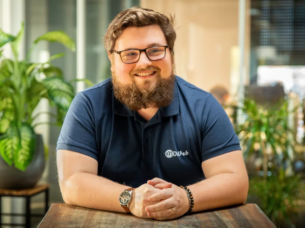Constantin souriant avec barbe et lunettes, polo MDWeb bleu
