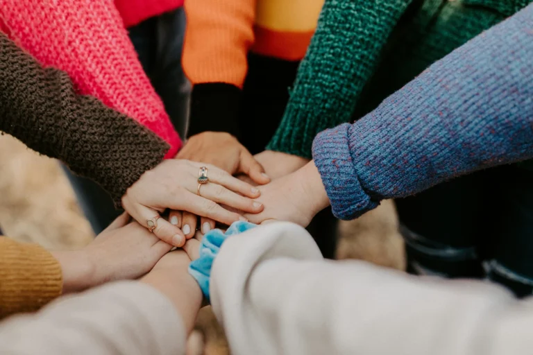 Plusieurs mains réunies et superposées au centre, symbolisant la solidarité et l'engagement RSE des sites e-commerce grâce à l'arrondi solidaire.