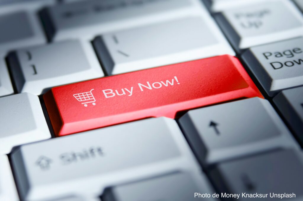Gros plan sur un clavier d'ordinateur avec une touche rouge Buy Now, illustrant l'augmentation des ventes e-commerce lors du pic de trafic Q4 sur PrestaShop.
