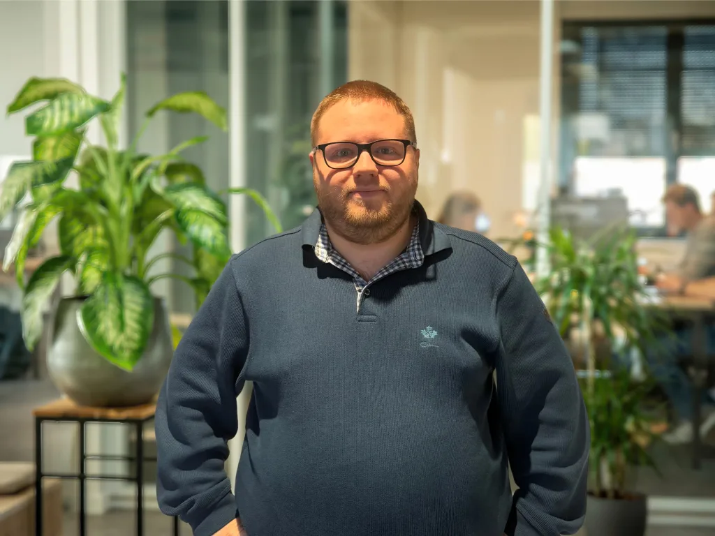 Homme à lunettes souriant dans un bureau moderne