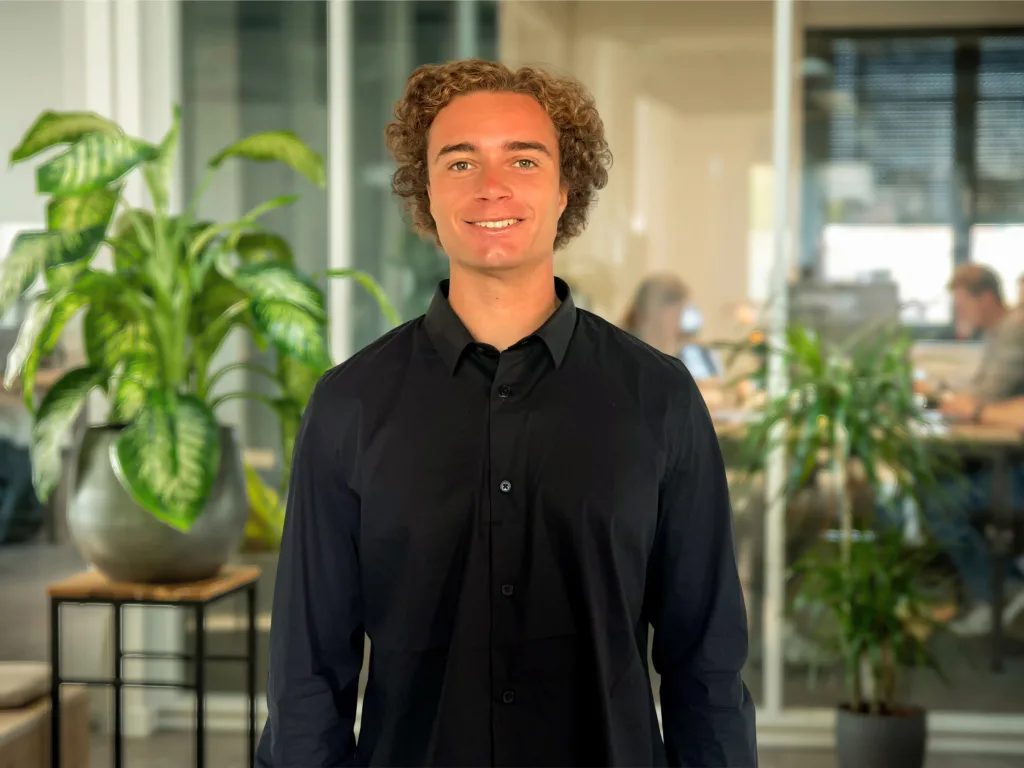 Jeune homme souriant en chemise noire au bureau